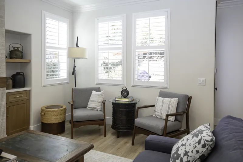 Sitting area with white shutters and wood shelving