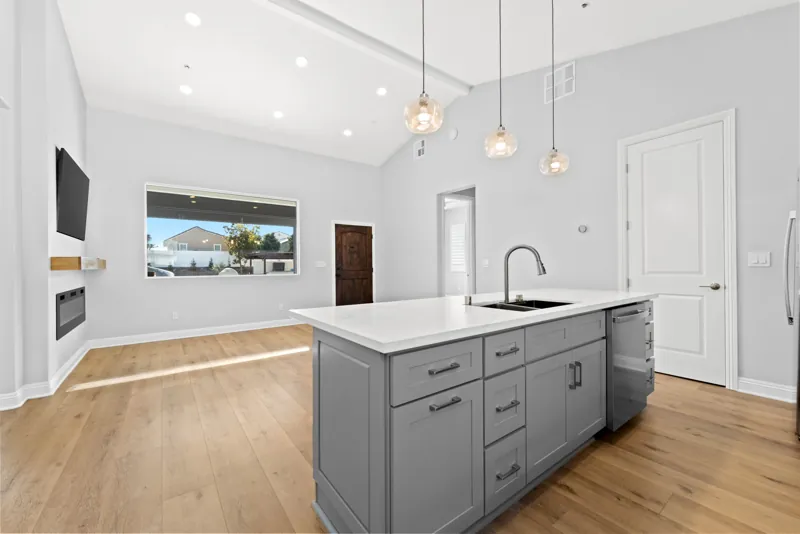 Kitchen island with gray cabinetry and pendant lights